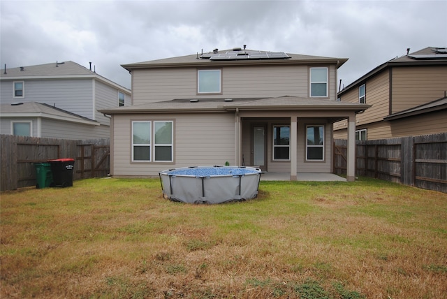 back of house featuring a fenced in pool and a lawn