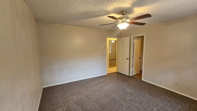 spare room with dark colored carpet, ceiling fan, and a textured ceiling