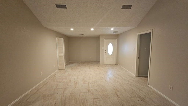 spare room with a textured ceiling and light hardwood / wood-style flooring