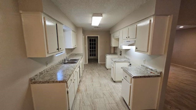 kitchen with white cabinetry, a textured ceiling, independent washer and dryer, and sink