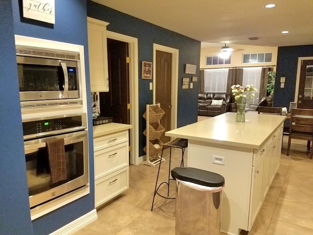 kitchen featuring a center island, appliances with stainless steel finishes, a kitchen bar, and white cabinets