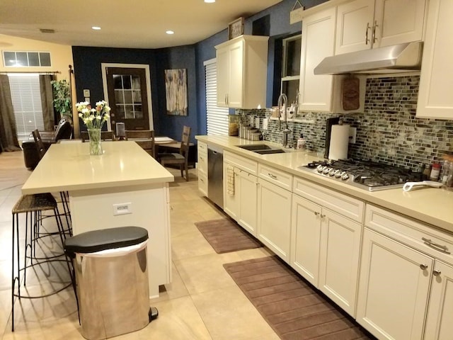 kitchen with light tile patterned floors, appliances with stainless steel finishes, a breakfast bar, sink, and a center island