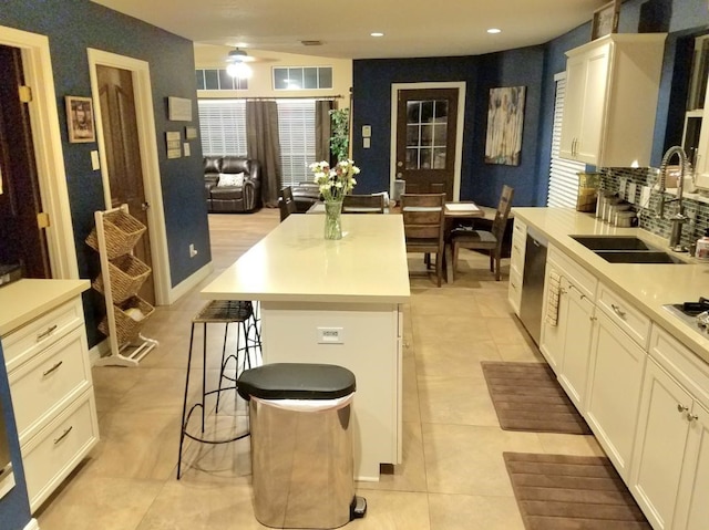 kitchen with light tile patterned floors, a kitchen breakfast bar, a kitchen island, dishwasher, and sink