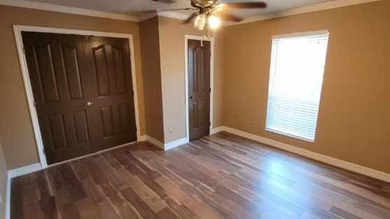 unfurnished bedroom with ornamental molding, a closet, dark hardwood / wood-style floors, and ceiling fan