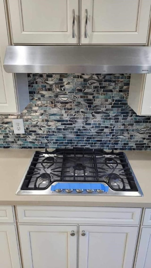 details featuring white cabinetry, tasteful backsplash, and black gas stovetop