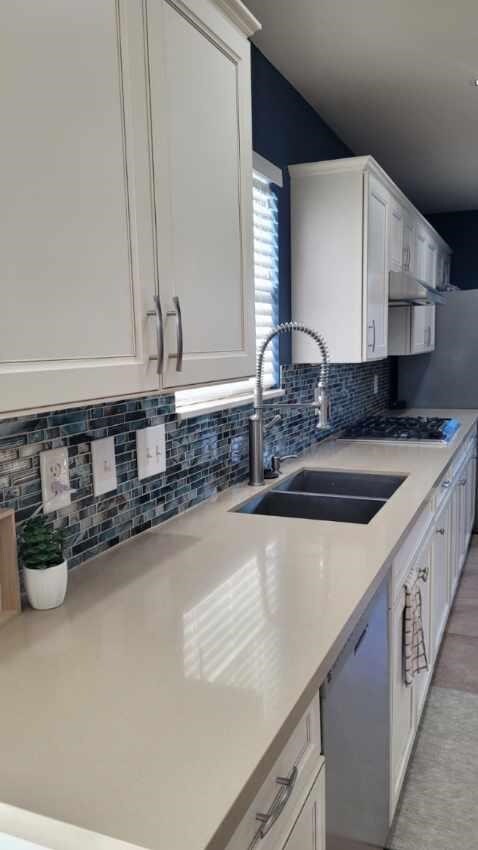 kitchen featuring white cabinets, stainless steel dishwasher, sink, and backsplash