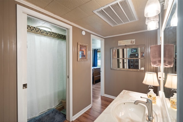 bathroom with hardwood / wood-style flooring, crown molding, and vanity