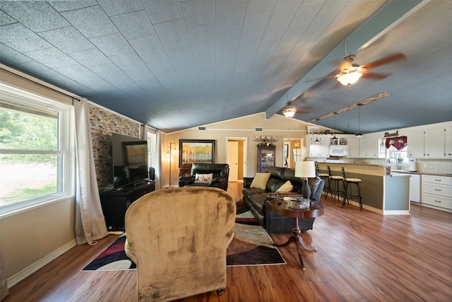 living room featuring ceiling fan, hardwood / wood-style flooring, vaulted ceiling with beams, and sink