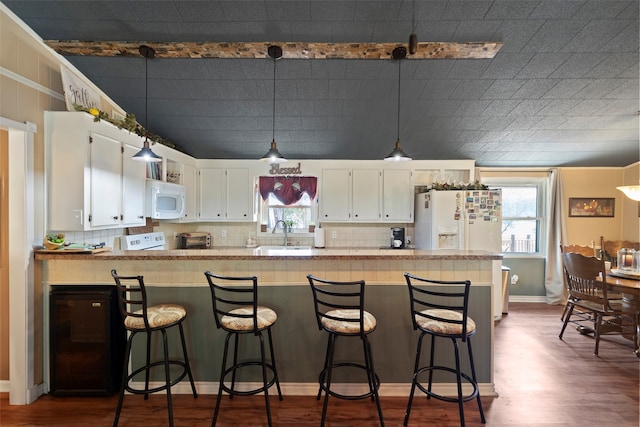 kitchen featuring kitchen peninsula, plenty of natural light, white cabinets, and white appliances