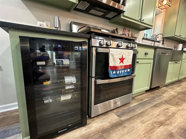 kitchen featuring green cabinets, light hardwood / wood-style floors, beverage cooler, and stainless steel appliances