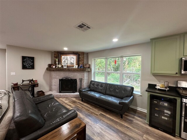 living room with dark hardwood / wood-style flooring, a fireplace, beverage cooler, and brick wall