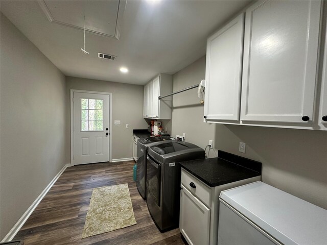 laundry area featuring dark hardwood / wood-style flooring, separate washer and dryer, and cabinets