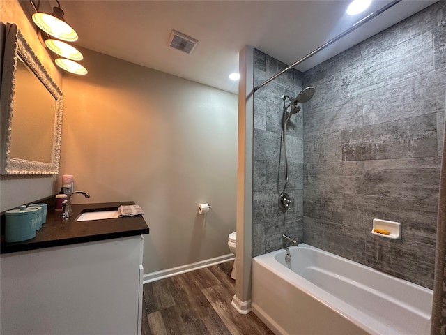 full bathroom featuring wood-type flooring, toilet, tiled shower / bath, and vanity