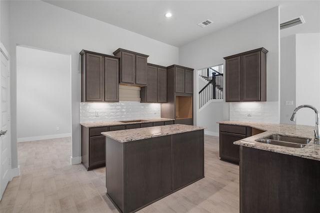 kitchen featuring backsplash, sink, light stone counters, and light wood-type flooring