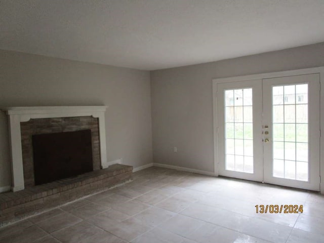 unfurnished living room featuring tile patterned flooring, a fireplace, and french doors