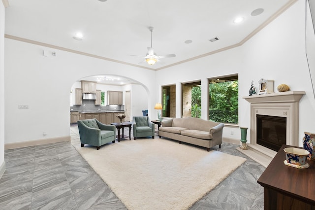 tiled living room with ceiling fan and ornamental molding