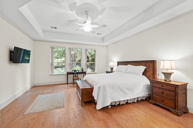 bedroom featuring ceiling fan, a raised ceiling, and light hardwood / wood-style flooring