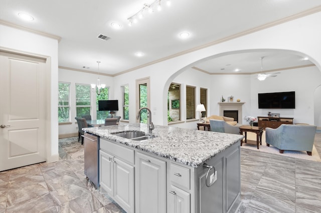 kitchen with dishwasher, sink, light stone counters, a center island with sink, and ceiling fan with notable chandelier