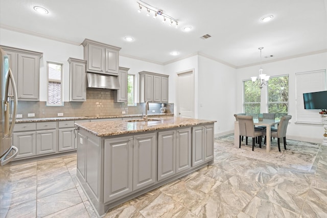 kitchen with light tile patterned floors, sink, gray cabinets, and a kitchen island with sink