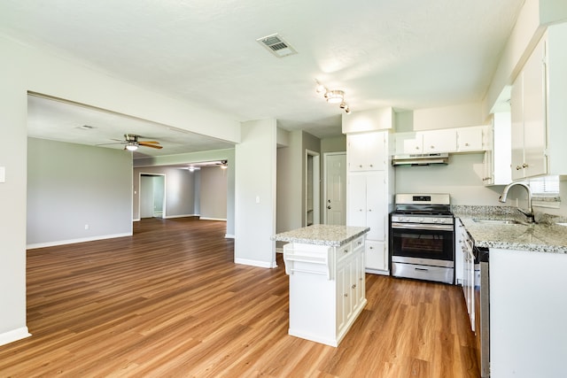 kitchen with appliances with stainless steel finishes, light hardwood / wood-style floors, white cabinets, a kitchen island, and ceiling fan