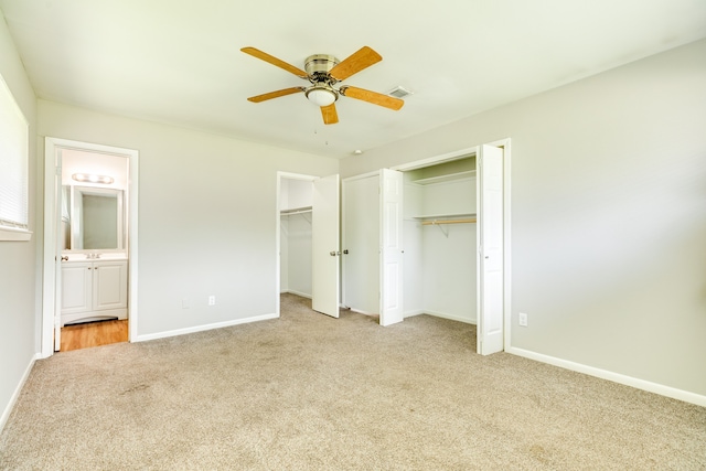 unfurnished bedroom featuring ceiling fan, light colored carpet, and ensuite bathroom