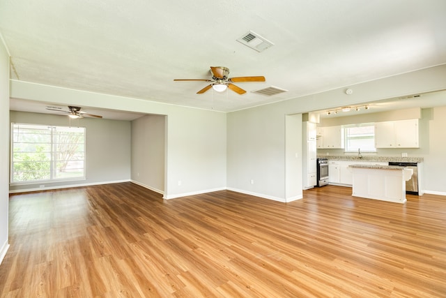 unfurnished living room featuring sink, ceiling fan, and light wood-type flooring