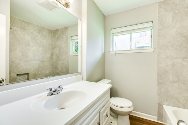 bathroom featuring vanity, a healthy amount of sunlight, hardwood / wood-style floors, and toilet