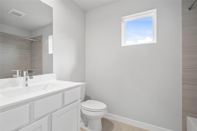 bathroom with a tile shower, vanity, and toilet