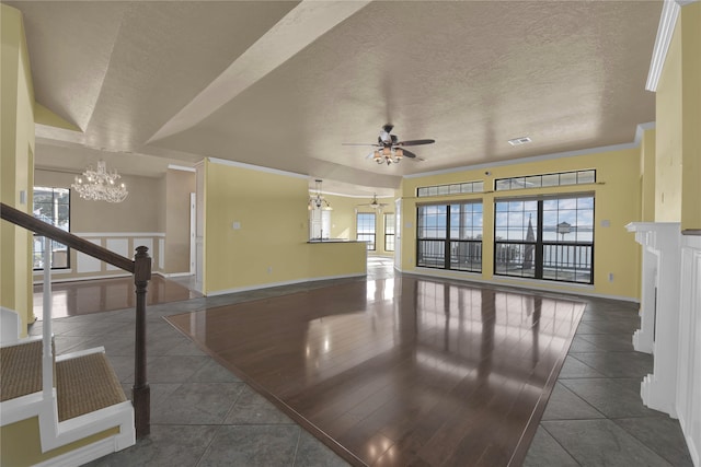 interior space with ceiling fan with notable chandelier, a healthy amount of sunlight, ornamental molding, and dark tile patterned flooring