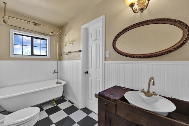 bathroom featuring tile patterned flooring, a washtub, vanity, and toilet