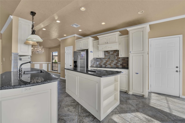 kitchen with backsplash, sink, tile patterned floors, stainless steel fridge, and hanging light fixtures