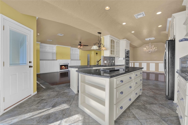 kitchen featuring backsplash, tile patterned flooring, ceiling fan with notable chandelier, appliances with stainless steel finishes, and a center island