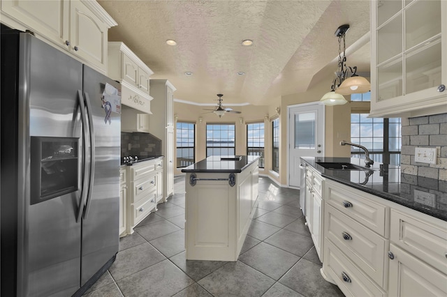 kitchen with dark tile patterned flooring, decorative backsplash, a textured ceiling, a kitchen island, and stainless steel fridge