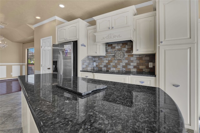 kitchen with a chandelier, crown molding, light wood-type flooring, stainless steel fridge, and dark stone countertops