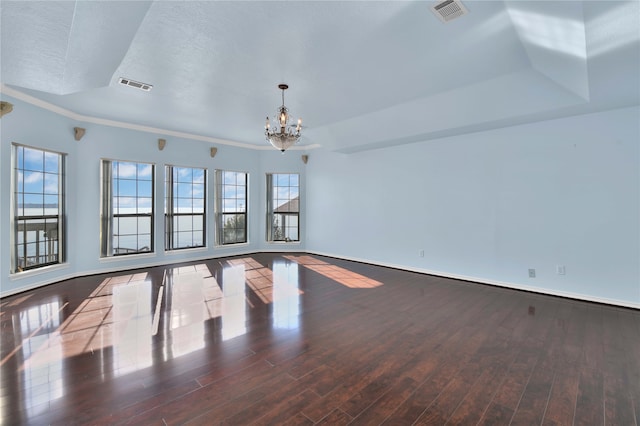 empty room featuring a wealth of natural light, a notable chandelier, and hardwood / wood-style flooring