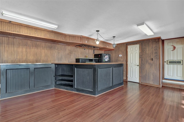 kitchen with wood walls, black refrigerator, dark hardwood / wood-style flooring, and crown molding