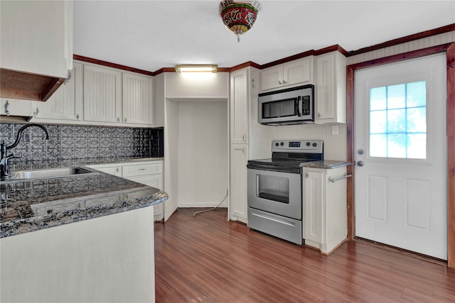 kitchen with appliances with stainless steel finishes, decorative backsplash, white cabinetry, sink, and dark wood-type flooring