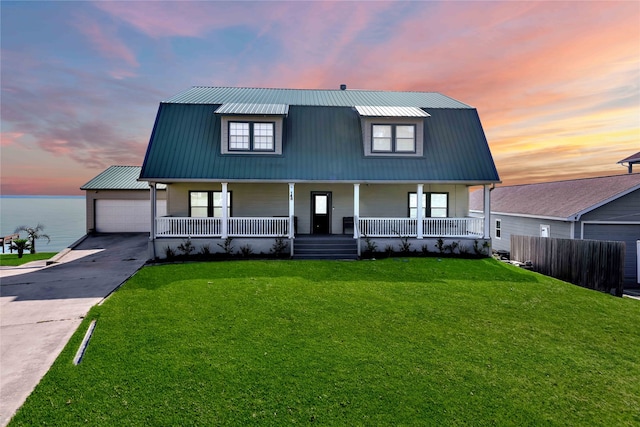 view of front of property featuring a garage, a lawn, a porch, and a water view