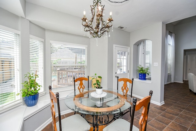 dining area featuring arched walkways, a chandelier, visible vents, and baseboards