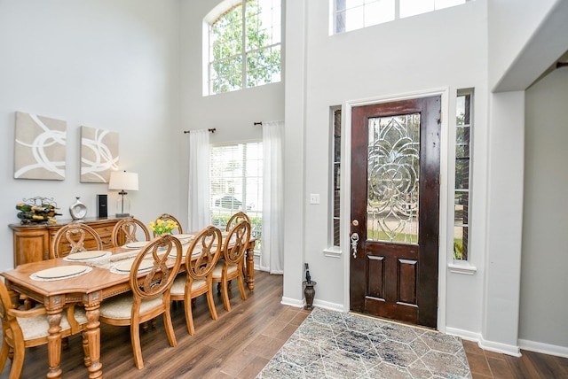 entryway with a high ceiling, dark wood-type flooring, and baseboards