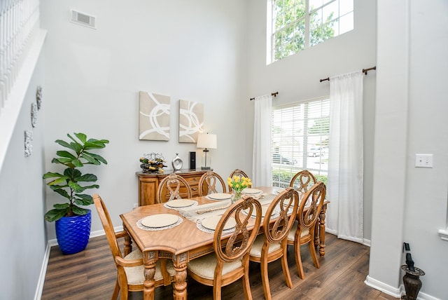 dining area featuring a high ceiling, dark wood finished floors, visible vents, and a healthy amount of sunlight