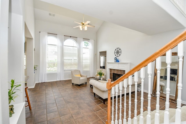 interior space featuring visible vents, stairway, a tiled fireplace, vaulted ceiling, and ceiling fan