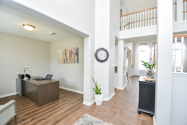 office with a high ceiling, wood finished floors, visible vents, and baseboards