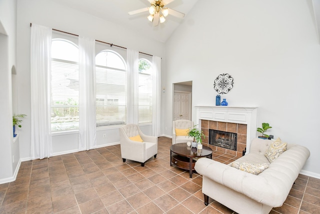 living area with high vaulted ceiling, ceiling fan, baseboards, and a tile fireplace