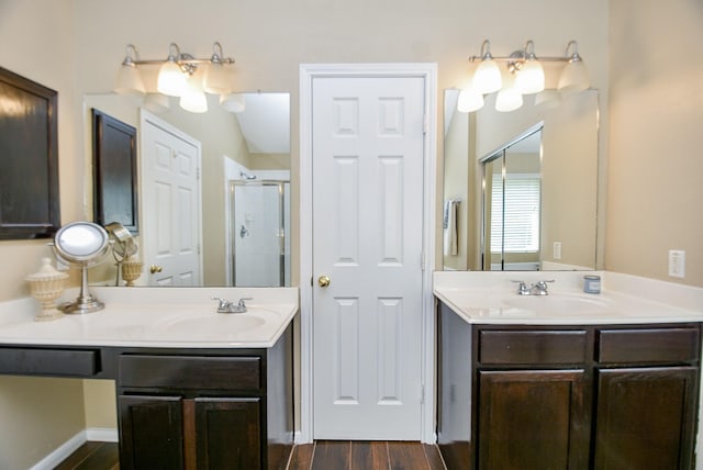 bathroom featuring a stall shower, two vanities, a sink, and wood finished floors