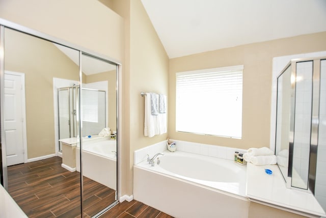 full bath featuring a stall shower, wood finish floors, lofted ceiling, and a bath