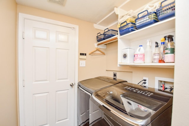 clothes washing area featuring laundry area, visible vents, and washing machine and clothes dryer