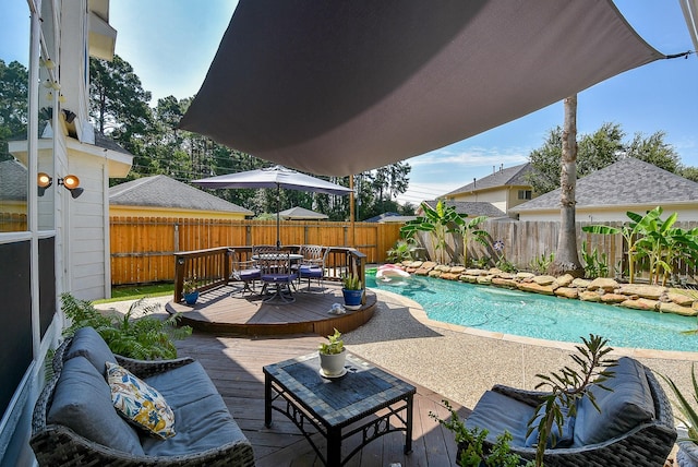 view of swimming pool with a wooden deck, outdoor dining area, a fenced backyard, and a fenced in pool