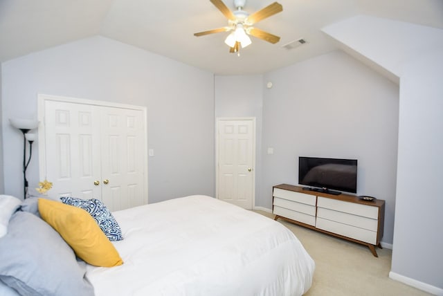 bedroom with a closet, visible vents, light carpet, vaulted ceiling, and ceiling fan