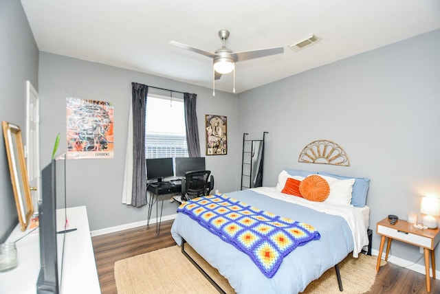 bedroom featuring a ceiling fan, wood finished floors, visible vents, and baseboards